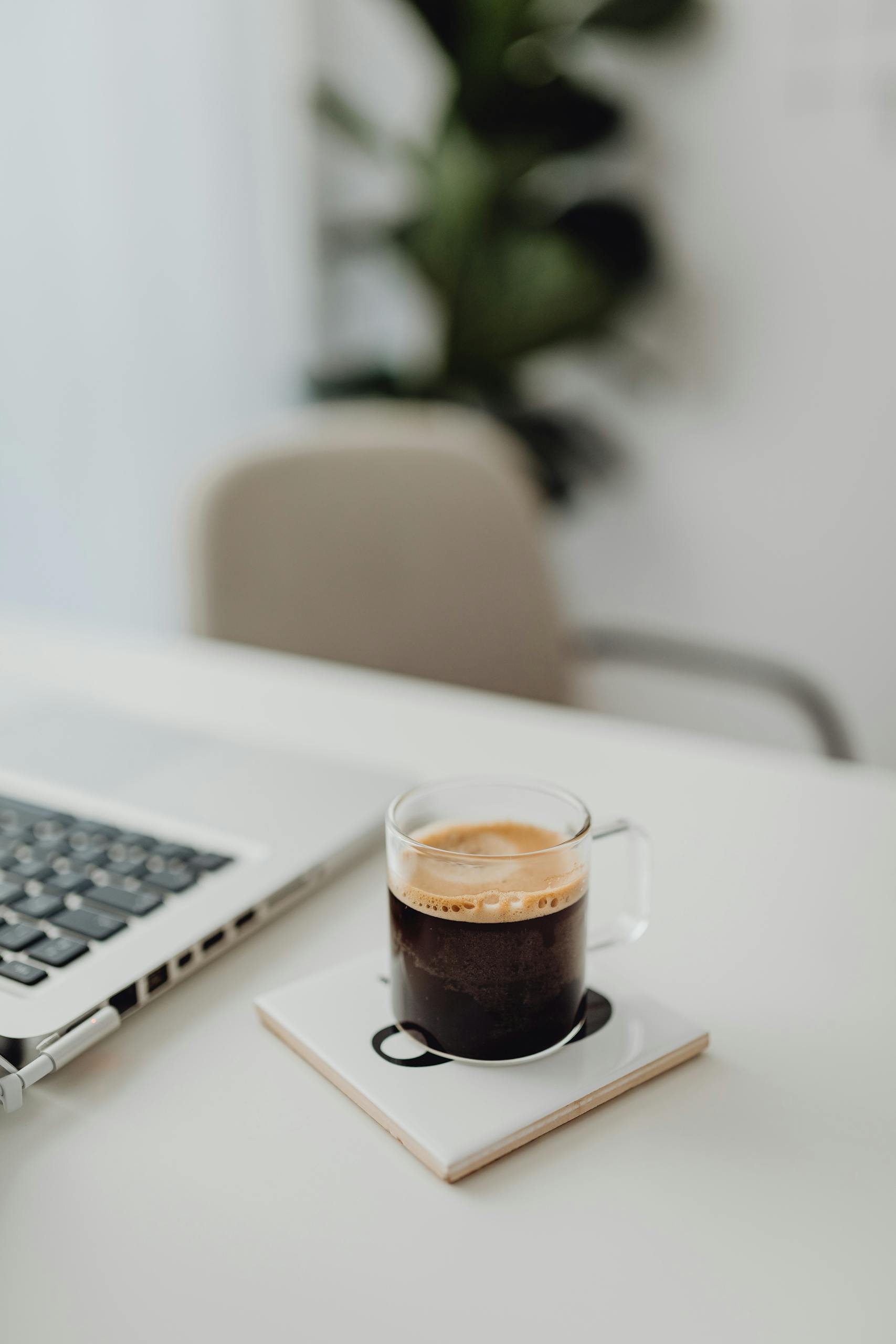 A clean and modern workspace featuring a coffee cup and laptop on a desk.